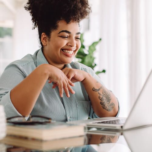 Woman, smiling while looking a laptop.