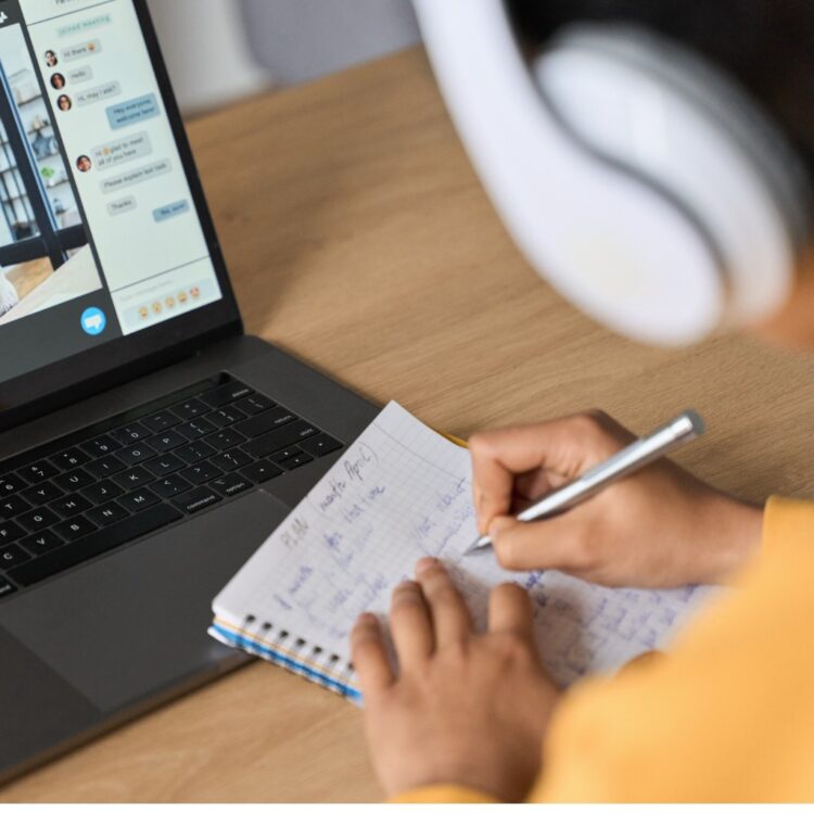 Woman recording notes in online meeting with man